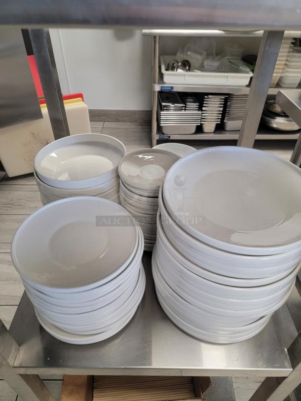 Stainless steel kitchen shelving unit with ceramic plates, bowls, and professional sheet pans. Ideal for commercial use.