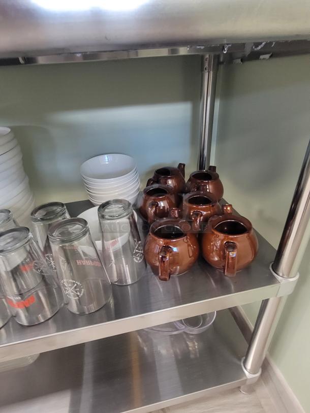 Stainless steel coffee station with brown mugs, clear glasses, and white plates. Includes Bene Casa espresso maker and neon sign.