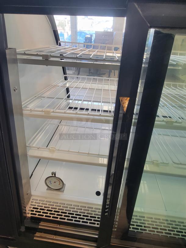 True TGM-R-48-SC/SC-B-W refrigerated display case with curved glass, rear sliding doors, and RCU Technology. Excellent condition.