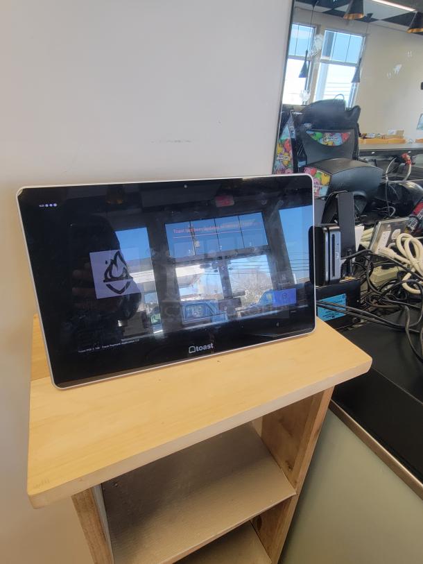 Toast POS system in excellent condition, featuring a touchscreen display on a wooden counter. Ideal for restaurants or retail.