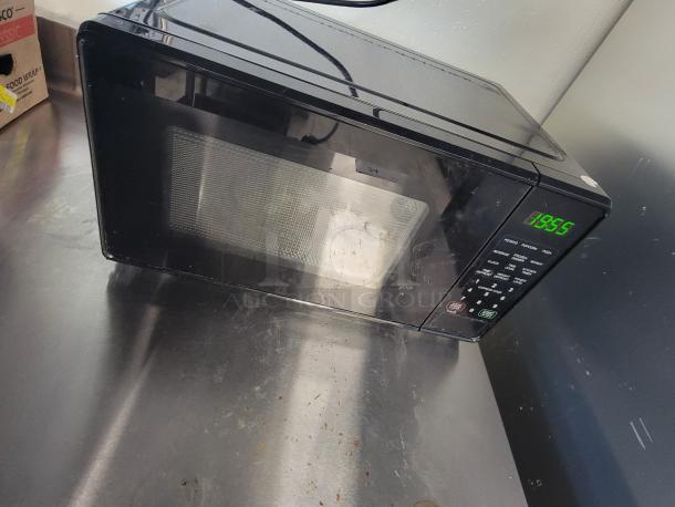 Commercial stainless steel prep table with a digital microwave on top. Durable surface, condition shows light wear.