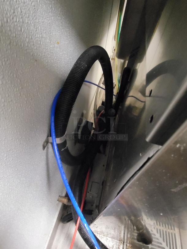 Hobart LXe high temp sanitizing commercial dishwasher rear view with visible hose connections and electrical wiring.