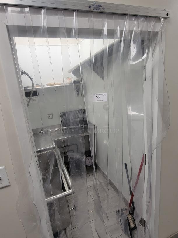 Commercial kitchen dish station with stainless steel equipment from KCS and Sapphire, behind a clear strip curtain, in excellent condition.