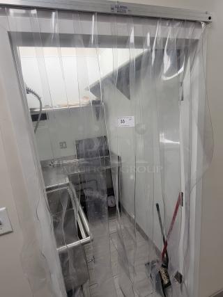 Commercial kitchen dish station with stainless steel equipment from KCS and Sapphire, behind a clear strip curtain, in excellent condition.