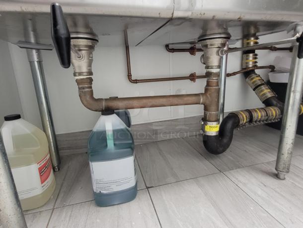 Under-sink view of commercial kitchen dish station bundle, showing plumbing and cleaning supplies. Stainless steel, heavy-duty construction.