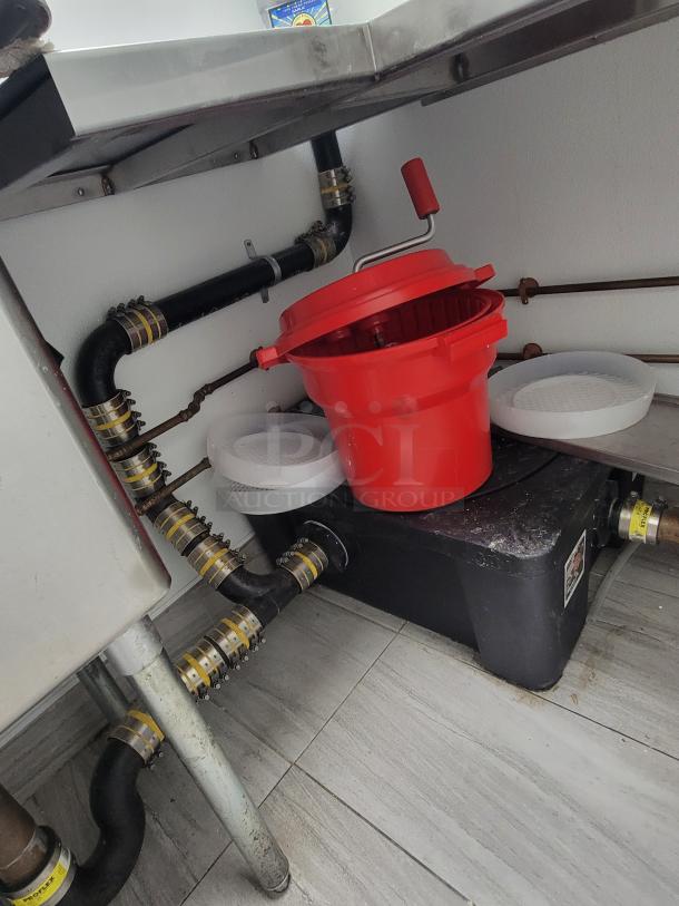 Stainless steel commercial kitchen dish station with pipes, red bucket, and prep accessories from KCS and Sapphire.