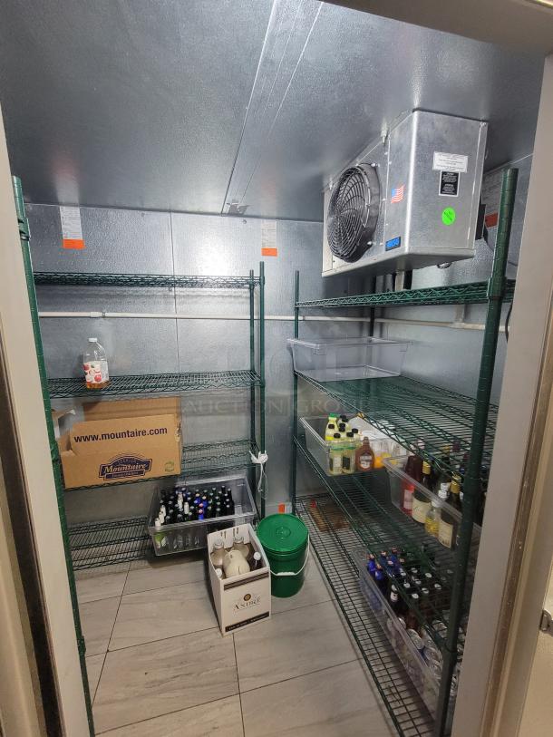 Norlake walk-in cooler, excellent condition, featuring wall-mounted condensing units and green Metro shelving racks for storage.