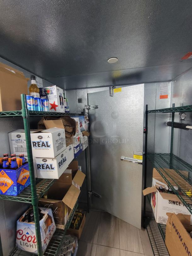 Norlake walk-in cooler interior with green Metro shelving, stocked with various beverage boxes, in excellent condition.