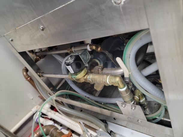 Interior of American Dish Service ET-Series dishwasher, showing plumbing and metal components. Durable and well-maintained.