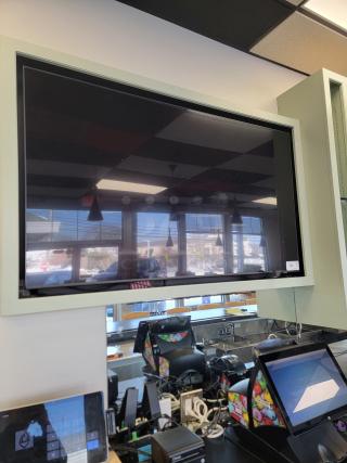 65" Samsung Smart TV Model UN65TU7000 mounted in restaurant, featuring thin bezels and Crystal 4K upscaling.