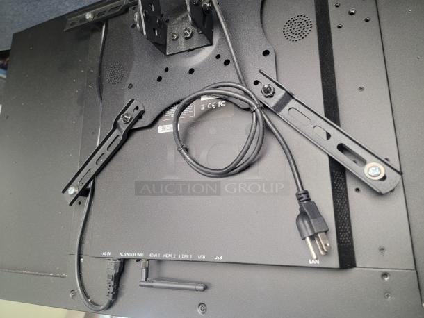 Samsung QM42 menu monitor back view with mounting brackets, power cord, and ports for HDMI, USB, and LAN. Commercial-grade.
