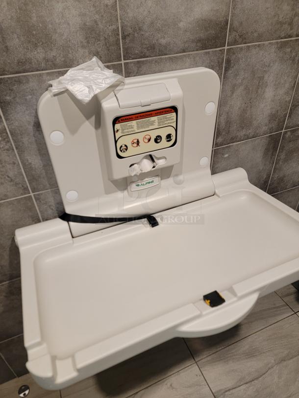 Alpine Industries wall-mounted baby changing station, model 400-01. Clean, durable antimicrobial plastic with liner dispenser and safety straps.