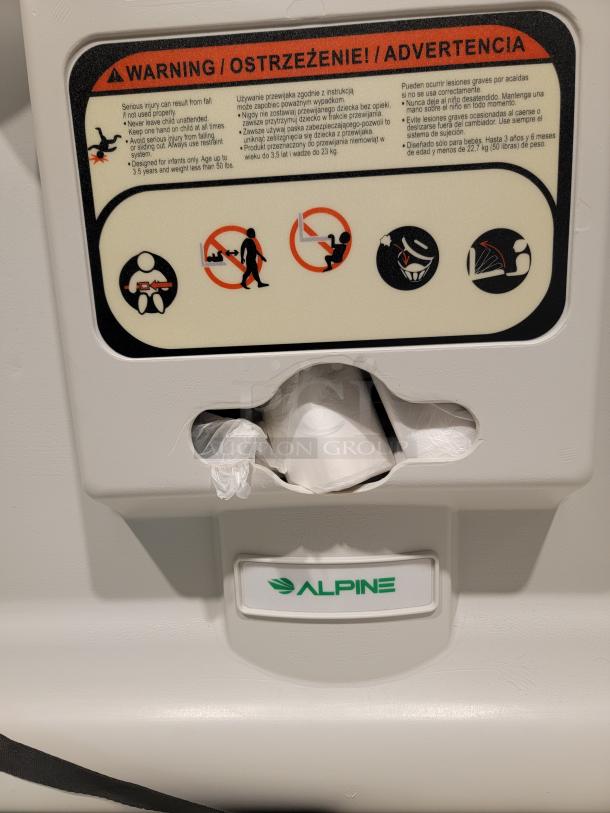 Alpine Industries wall-mounted baby changing station, model 400-01. Features liner dispenser and safety straps, antimicrobial plastic.