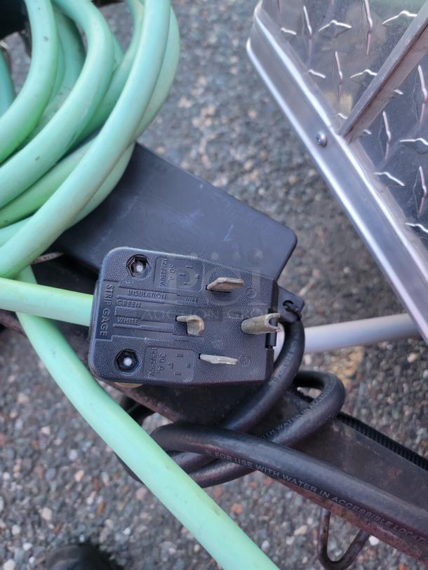 50A 125/250V RV-style plug on 2021 Covered Wagon 16' mobile food trailer with a green power cord.