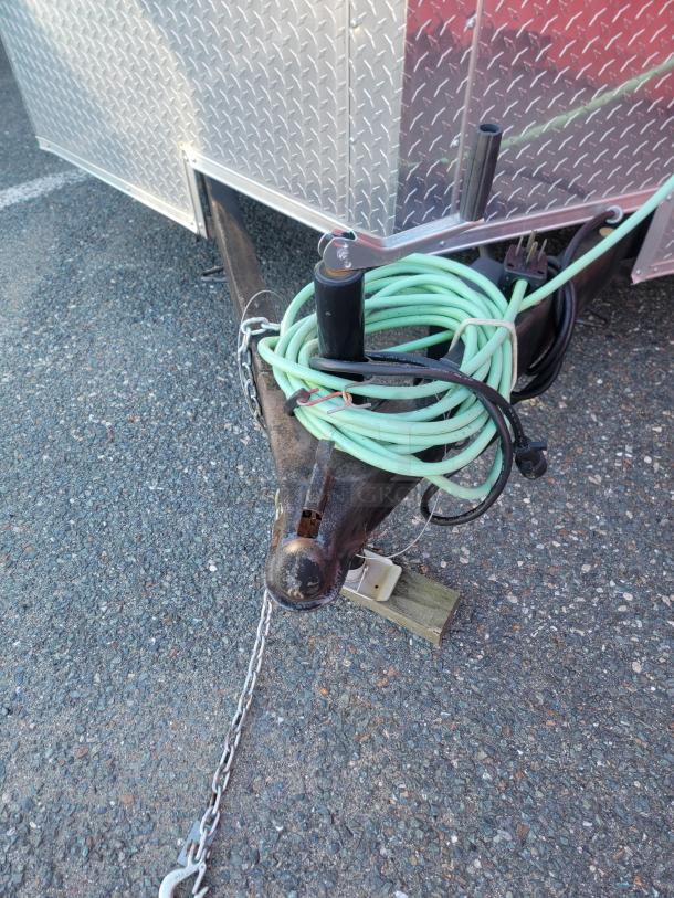 Drop hitch and electrical connections of a 2021 16' Covered Wagon Trailers mobile food trailer on gravel.