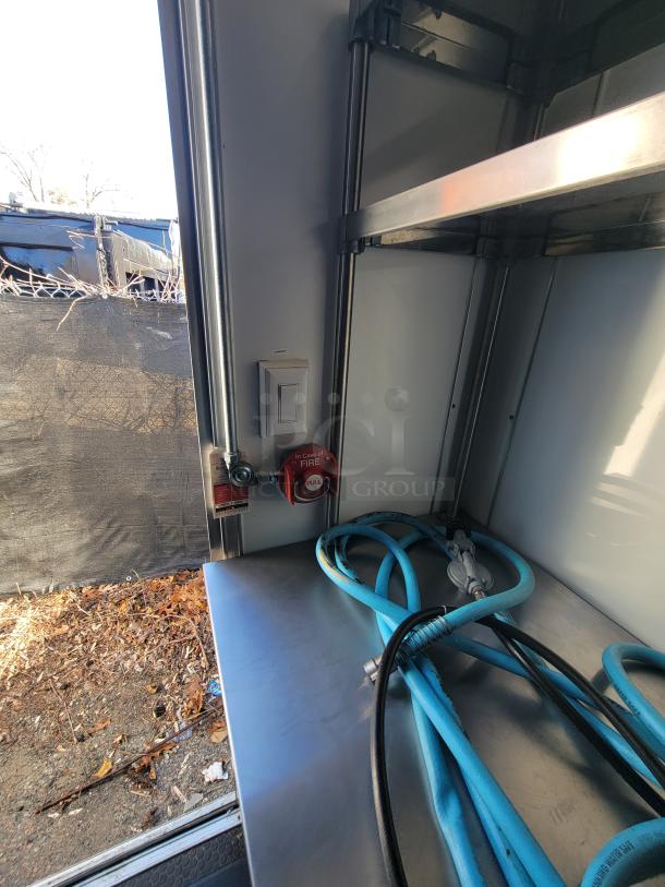 Interior of a 2021 Covered Wagon 16' mobile food trailer showing a stainless steel surface with hoses and a fire suppression pull station.
