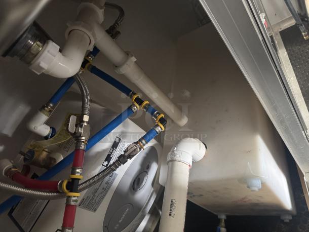 Bosch water heater and plumbing system inside a 2021 Covered Wagon 16' mobile food trailer, featuring labeled pipes and connectors.