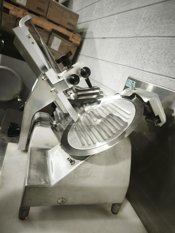 Patriot meat slicer with 10″ blade, stainless steel body, in used condition. Features adjustable knobs and safety guard.