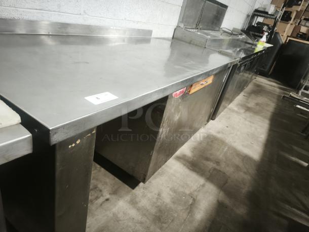 Stainless steel prep table with wooden drawer, good condition, features durable surface, suitable for kitchen use.