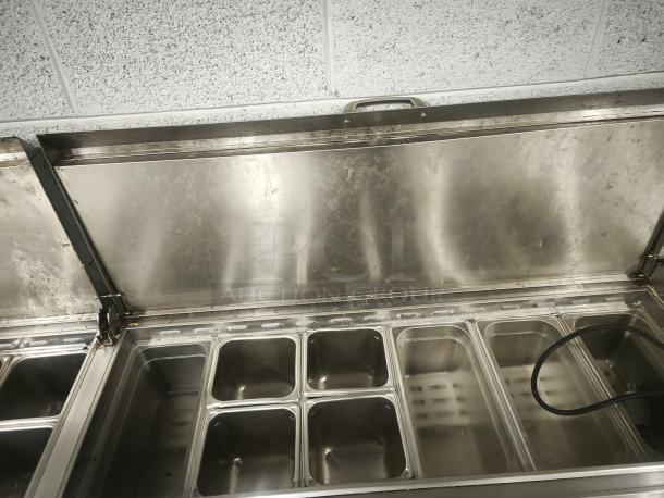 True TPP-93 93" 3-door refrigerated pizza prep table with stainless steel finish and open lids, showing insert compartments.