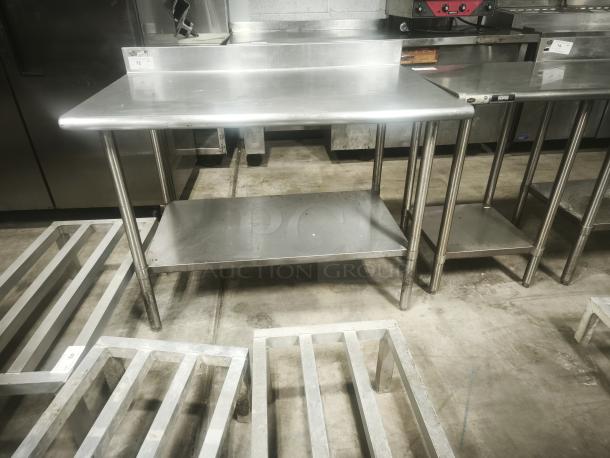 Economy stainless steel prep table, 30x30x36 inches, with backsplash and lower shelf. Good condition, ideal for kitchens.