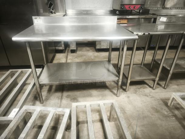 Stainless steel prep table, 30x30x36 inches, features undershelf, visible wear, ideal for kitchen use.