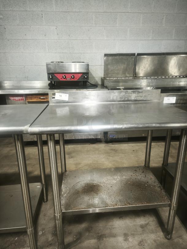Stainless steel prep table, 36x24x36 inches, used condition. Features durable top and bottom shelf. Auction tag visible.