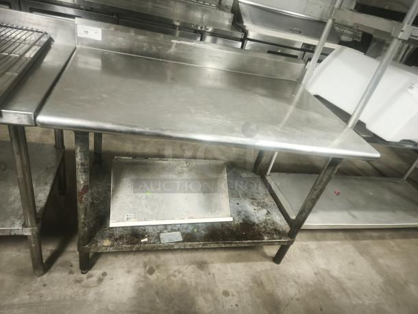 Economy stainless steel prep table, 42x30x34 inches, with backsplash and lower shelf, shows signs of wear and discoloration.