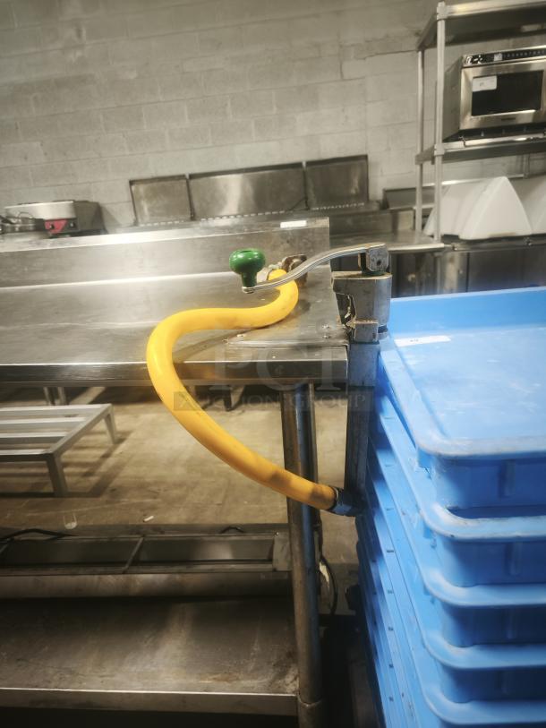 Stainless steel prep table, 95x31x36 inches, with mounted green nozzle and yellow hose. In good condition, ideal for kitchens.