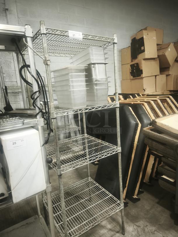 Stainless steel wire shelving unit with four shelves, sturdy condition, used. Tag displaying "21" is visible on top shelf.