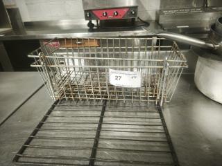 Commercial-grade stainless steel or chrome-plated wire basket, rectangular, used condition, label "27 QTY", kitchen setting.
