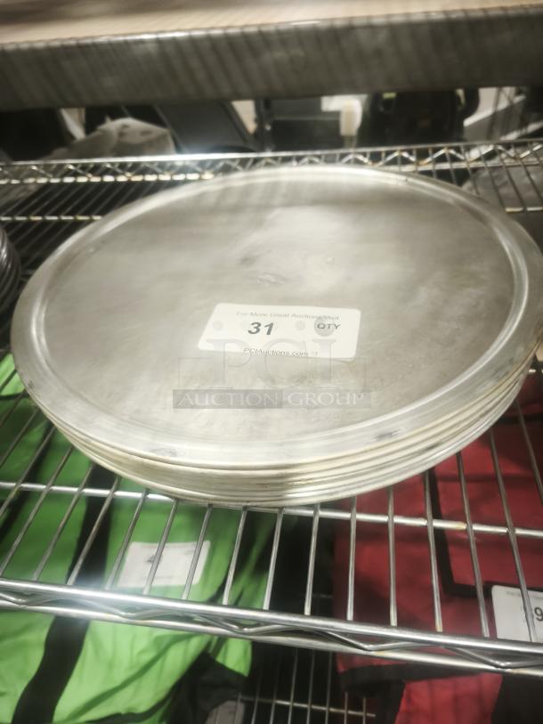 Stack of aluminum pizza pans on a metal shelf, showing label with quantity "31." Smooth surface, good condition.