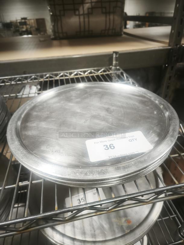 Aluminum pizza pans on metal rack, lightly used, with auction tag showing item number 36 for PCI Auctions.
