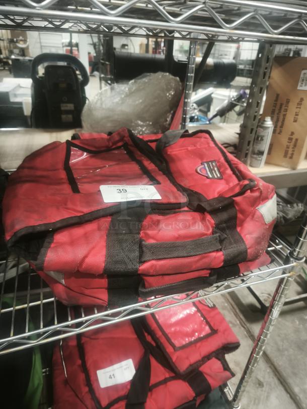 Commercial Products ProServe red insulated pizza delivery bag, dual handles, ID label visible, stored on metal shelf.