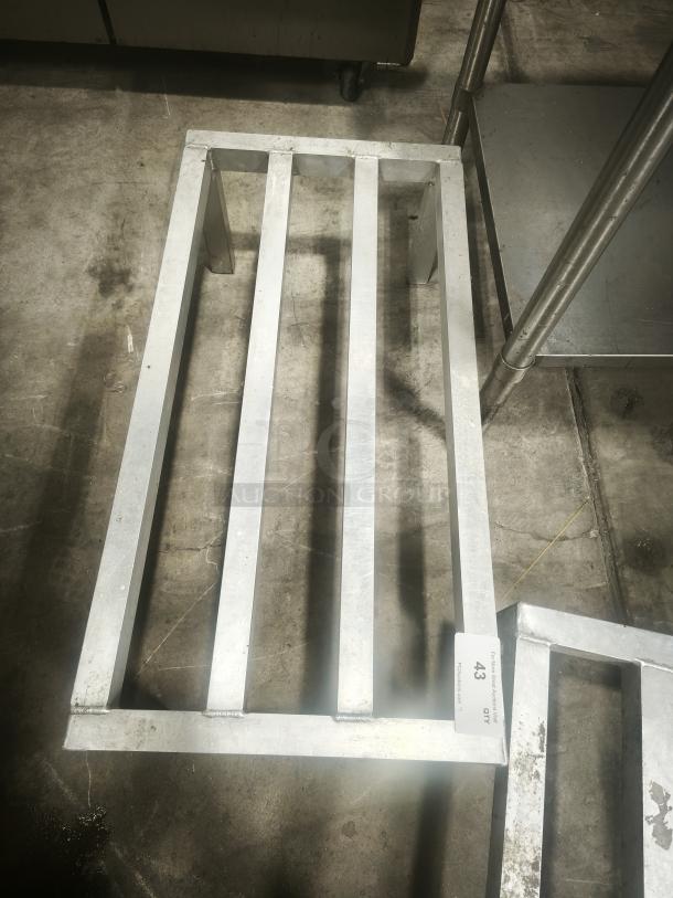 Aluminum dunnage rack for commercial storage, featuring a sturdy metal frame. Good condition with visible use wear.