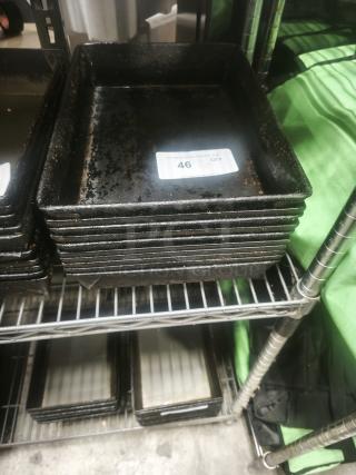 Stack of rectangular enamelware tin plate pans, showing signs of wear, with a visible label marked "46 QTY".
