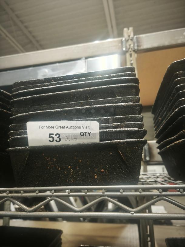 Stack of enamelware tin plate pans in used condition on a metal shelf, labeled with quantity "53 Qty" for auction display.