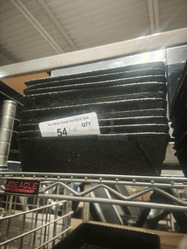 Stack of enamelware tin plate pans, slightly worn, on metal shelving. Tag reads "54, QTY." Marked with "EAGLE."