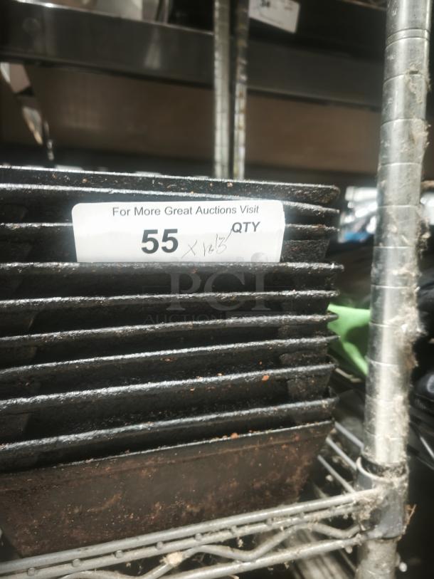 Stack of enamelware tin plate pans, showing signs of rust and wear, placed on a metal shelf. Numbered label "55" visible.
