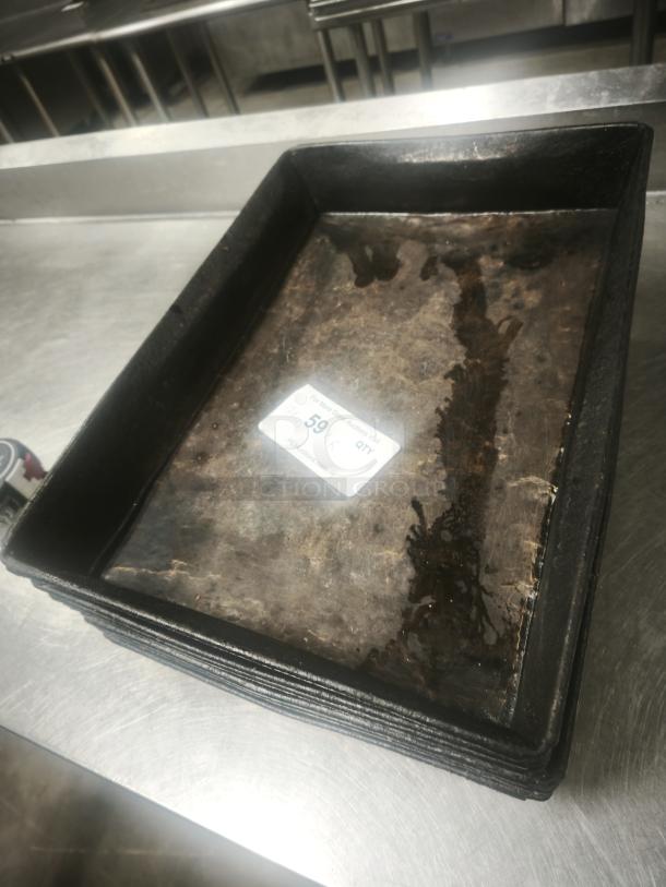 Stack of enamelware tin plate pans with aged patina, rectangular, showing wear, auction label number 59 visible.