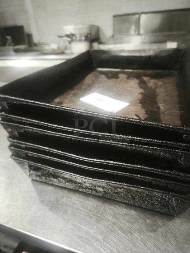 Stacked enamelware tin plate pans, used condition, visible wear, on a metal surface.