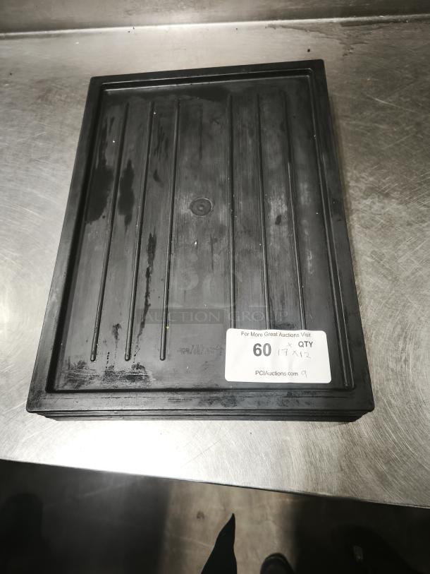 Black plastic tray or lid, rectangular, used condition, with visible markings and auction label showing "60 QTY 17 x 12."