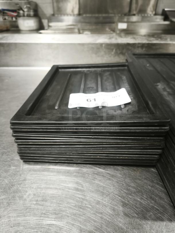 Stack of multi-purpose black plastic trays or lids, minor wear, rectangular shape, auction tag numbered 61.