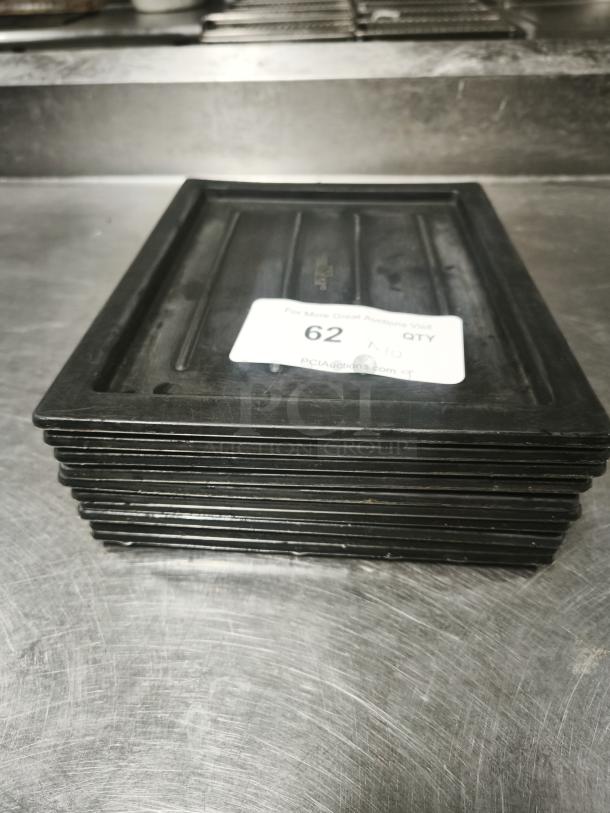 Stack of black plastic trays or lids with label "62 QTY," in good condition.