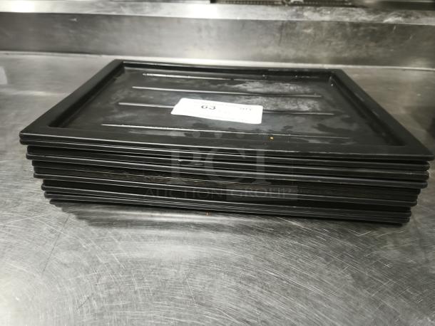 Stack of black plastic trays or lids, multi-purpose use, rectangular shape, good condition, number label visible.