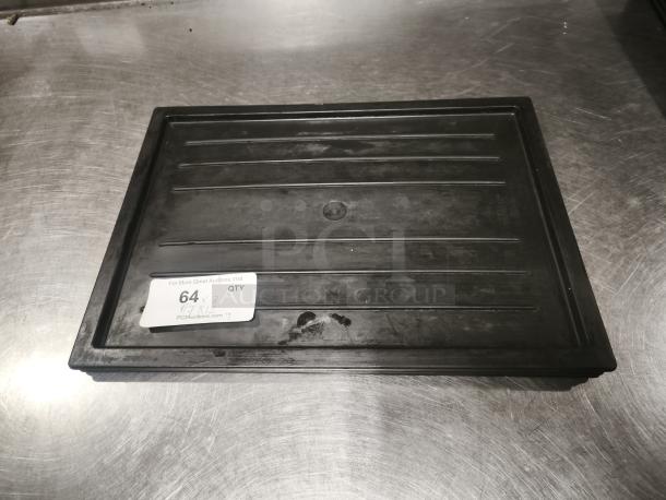 Black plastic tray or lid, multi-purpose, rectangular with ridges. Visible sticker with auction info. Good condition.