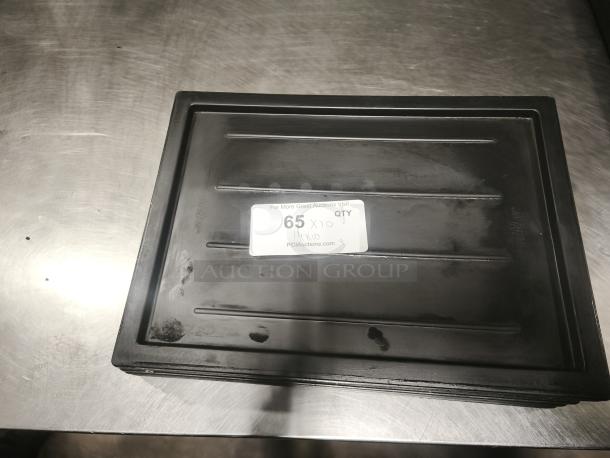 Black multi-purpose plastic tray or lid with textured surface. Visible label reads "65 QTY" and directs to PCIauctions.com. Signs of wear.