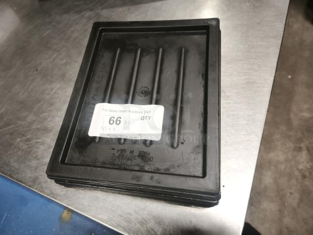 Black plastic tray or lid with ridged surface. Good condition. Auction label reads "66 QTY 10, PCIauctions.com".