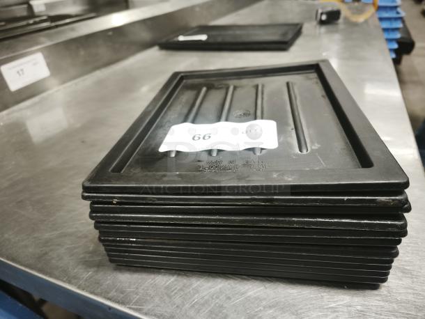 Multi-purpose black plastic tray or lid, stacked, with visible label marked "66". Used condition, some surface wear.