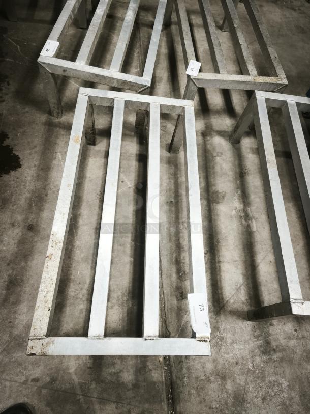 Metallic framework structure with visible rust, placed on a concrete floor. Labels marked '73' and '59' indicate item numbers.